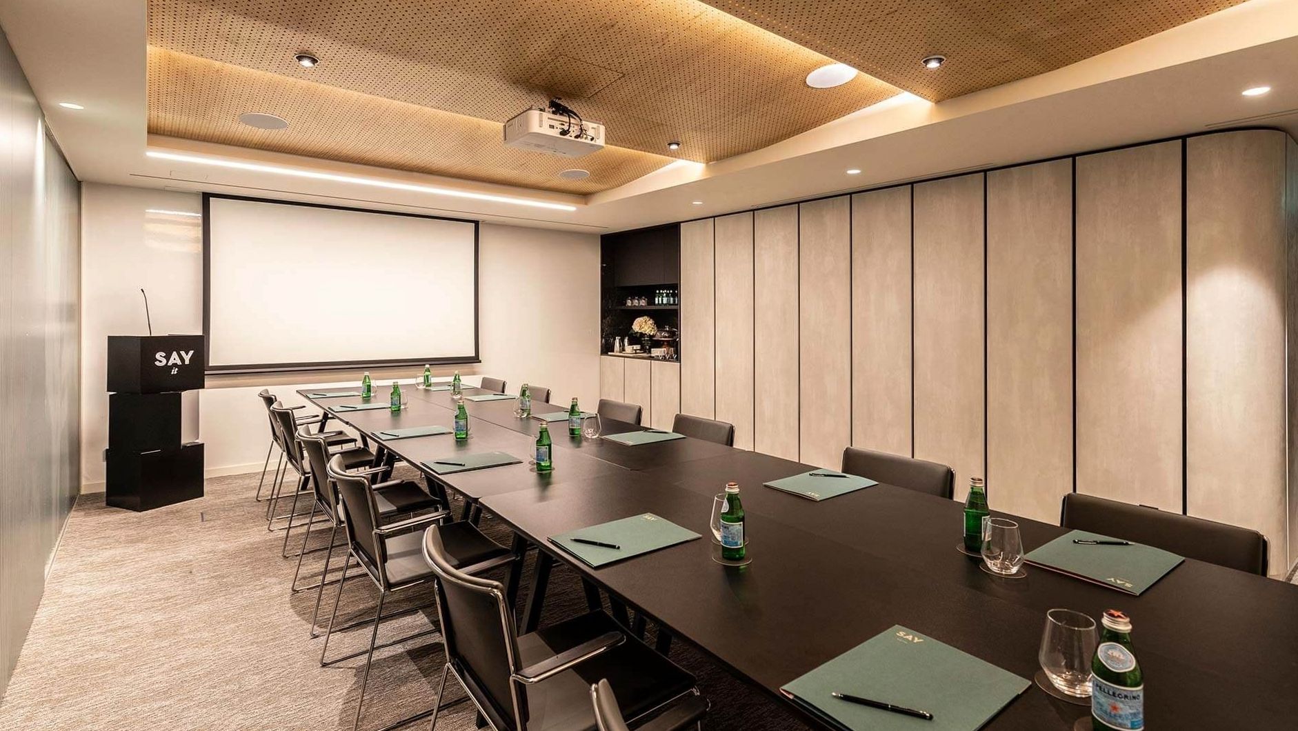 Casino salon with green felt card table, brass pendant lamps and dark timber panelling